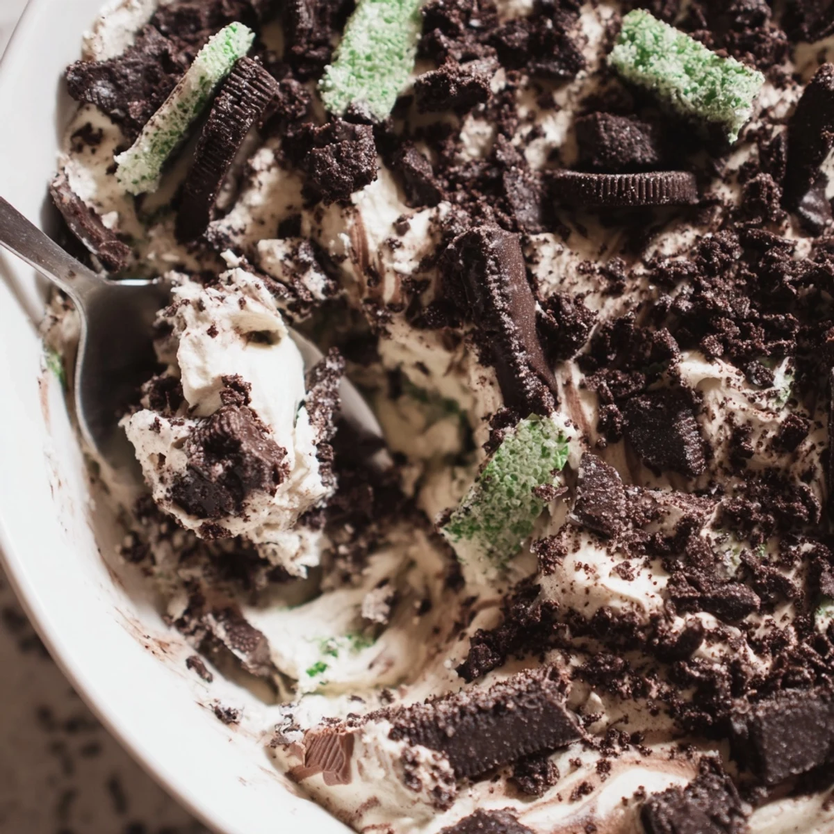 A spoon ready to serve Peppermint Crisp with Chocolate, revealing airy whipped cream and crunchy mint candy pieces.