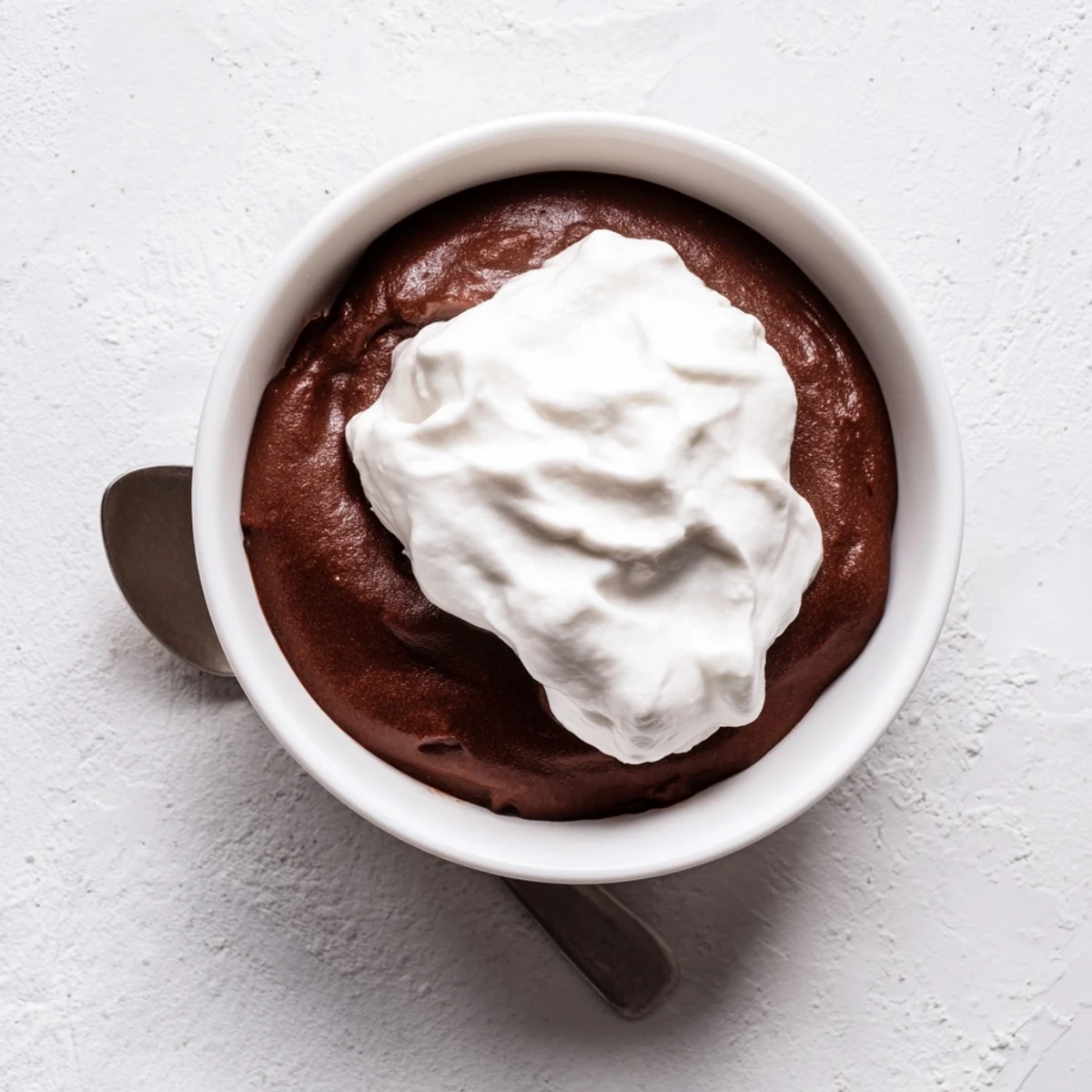Easy chocolate pudding topped with billowy whipped cream, served chilled with a fresh berry garnish for a sweet treat.