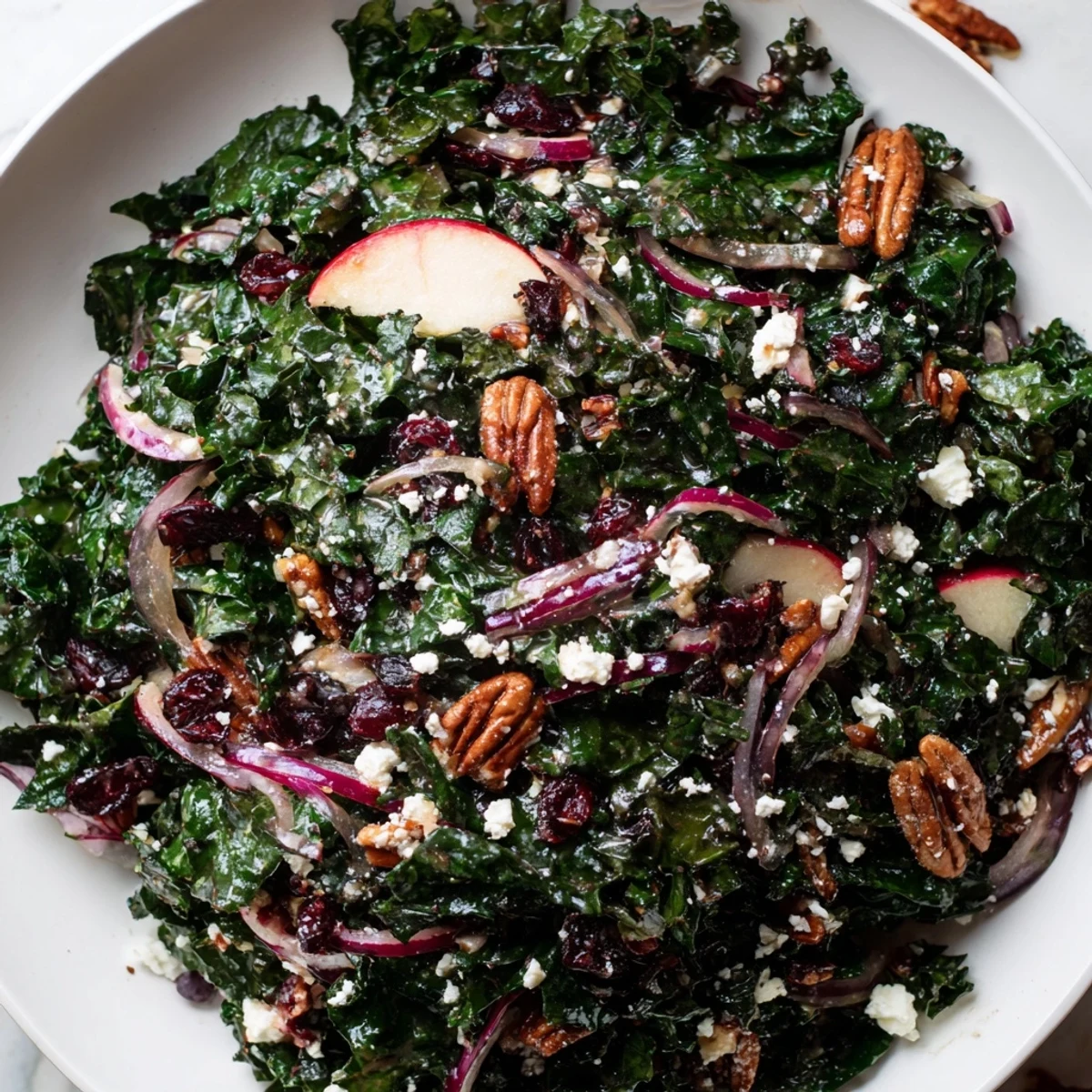 This easy, wholesome Winter Kale Salad with Pecans and Cranberries is tossed with crisp apple slices and red onion on a rustic serving board.  