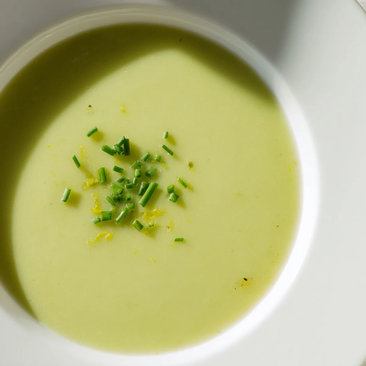 Creamy Asparagus Soup with Lemon steaming in a rustic bowl, garnished with fresh chives and lemon zest beside crusty bread.