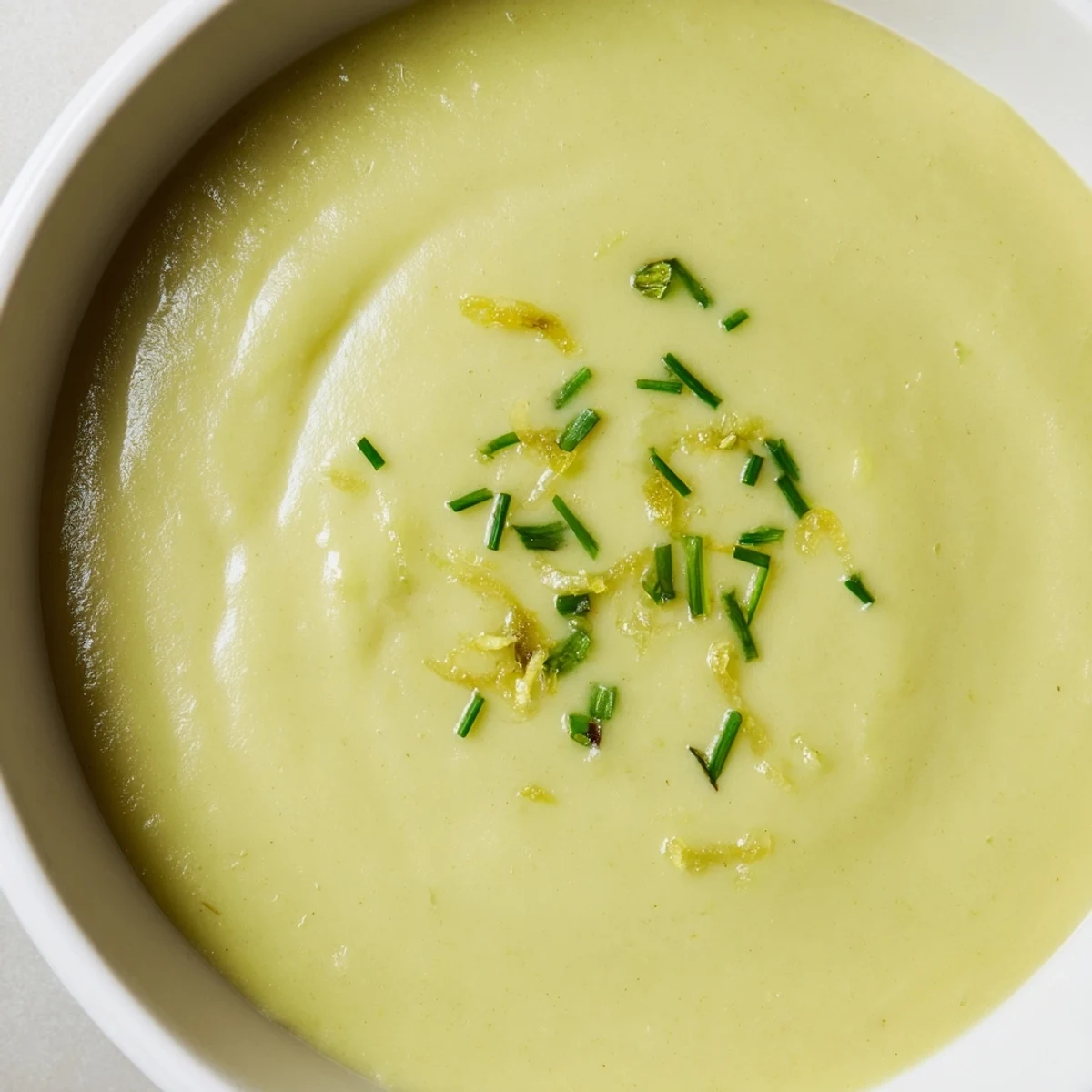 A vibrant green Creamy Asparagus Soup with Lemon ready to serve, featuring tender asparagus spears and a swirl of cream.
