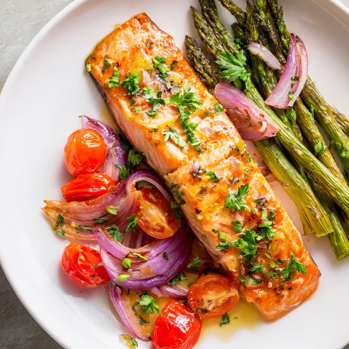Golden Sheet Pan Salmon with Asparagus and Tomatoes served with lemon wedges and parsley.