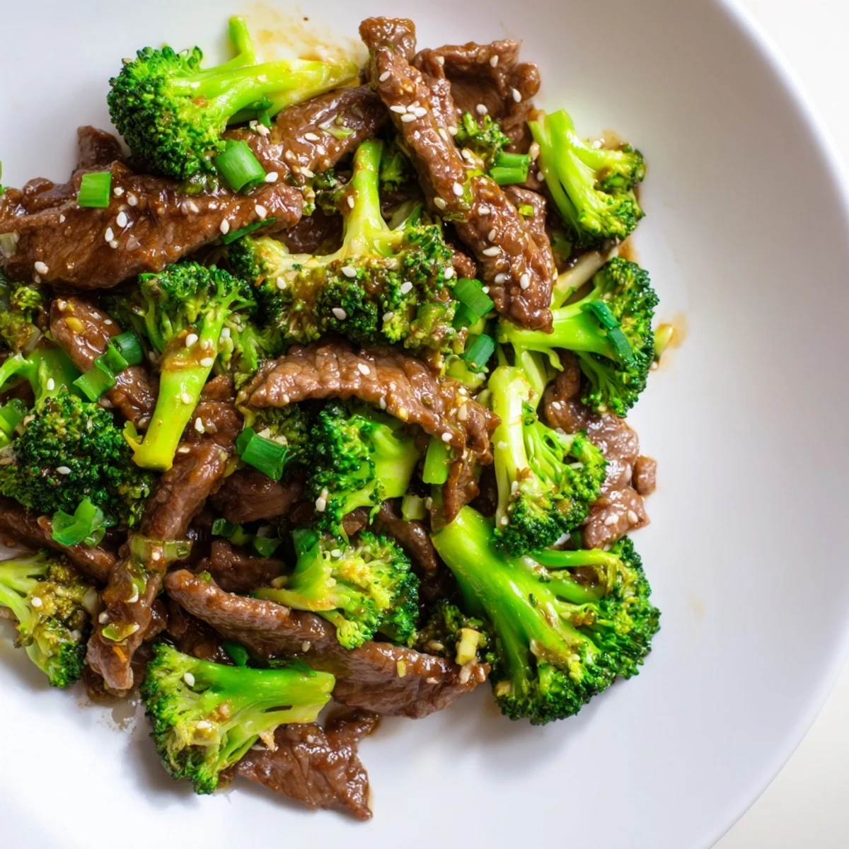 Steaming beef and broccoli in ginger soy sauce on a plate over jasmine rice.