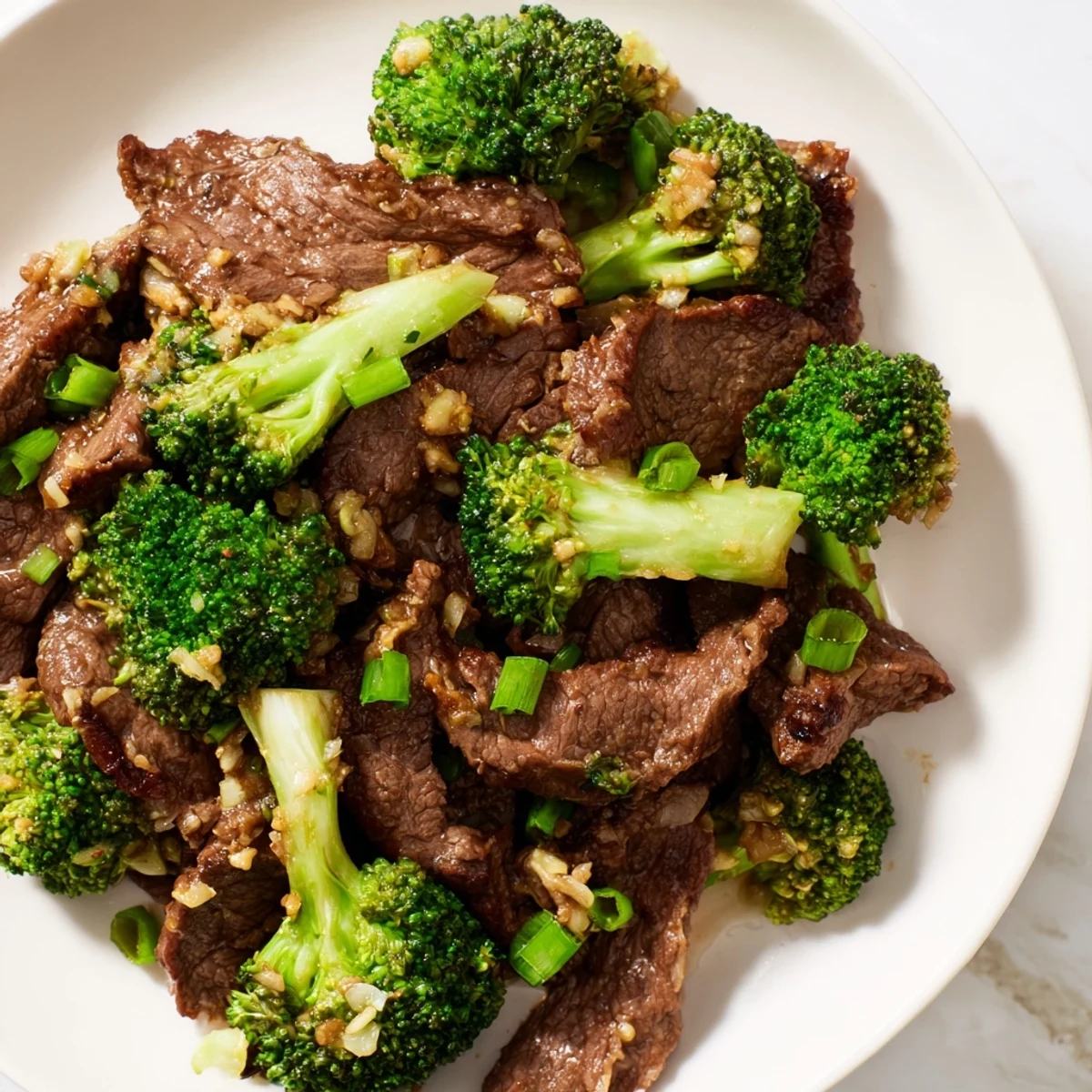Hot ginger-scented Beef and Broccoli Stir Fry with tender beef and bright green broccoli florets in a glossy sauce, served over fluffy white rice in a ceramic bowl.