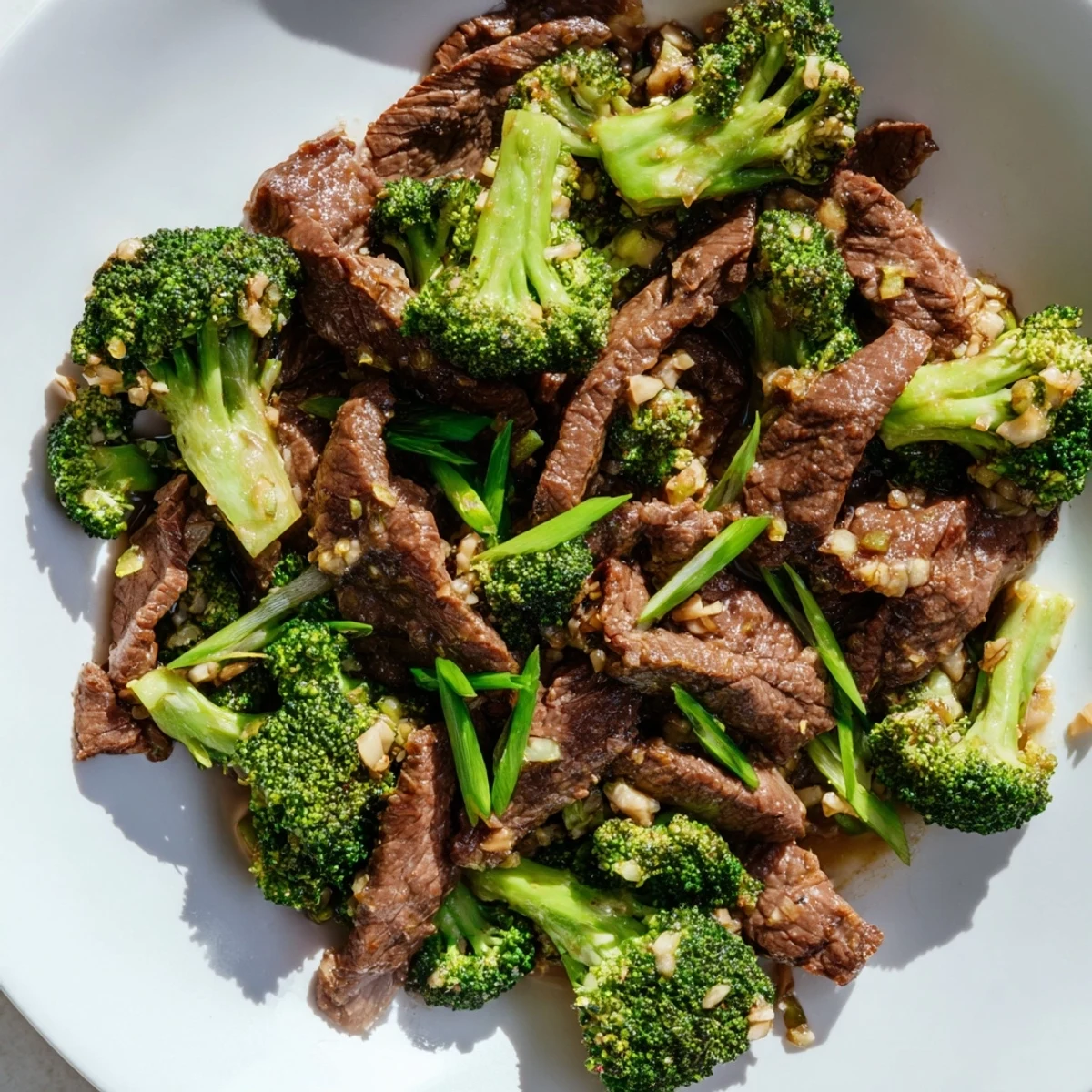 Close-up view of Beef and Broccoli Stir Fry showcasing juicy beef slices and crisp broccoli coated in savory ginger sauce, with chopsticks poised for a bite.