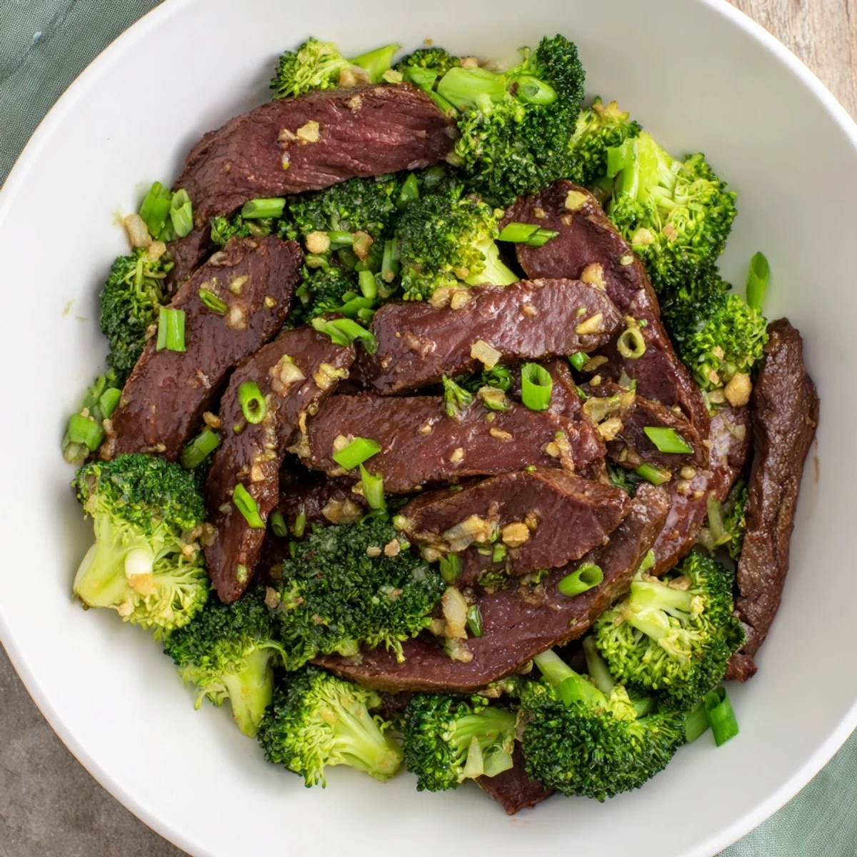 Beef and Broccoli Stir Fry plated with steamed jasmine rice and a sprinkle of green onions, steam rising from the hot, glossy ginger sauce.