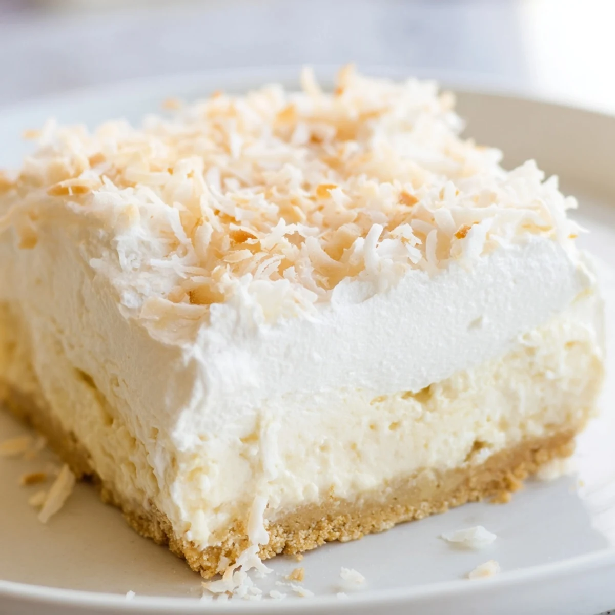 A close-up of Coconut Cream Dream Bars showing the crumbly graham crust, creamy coconut filling, and toasted flakes.