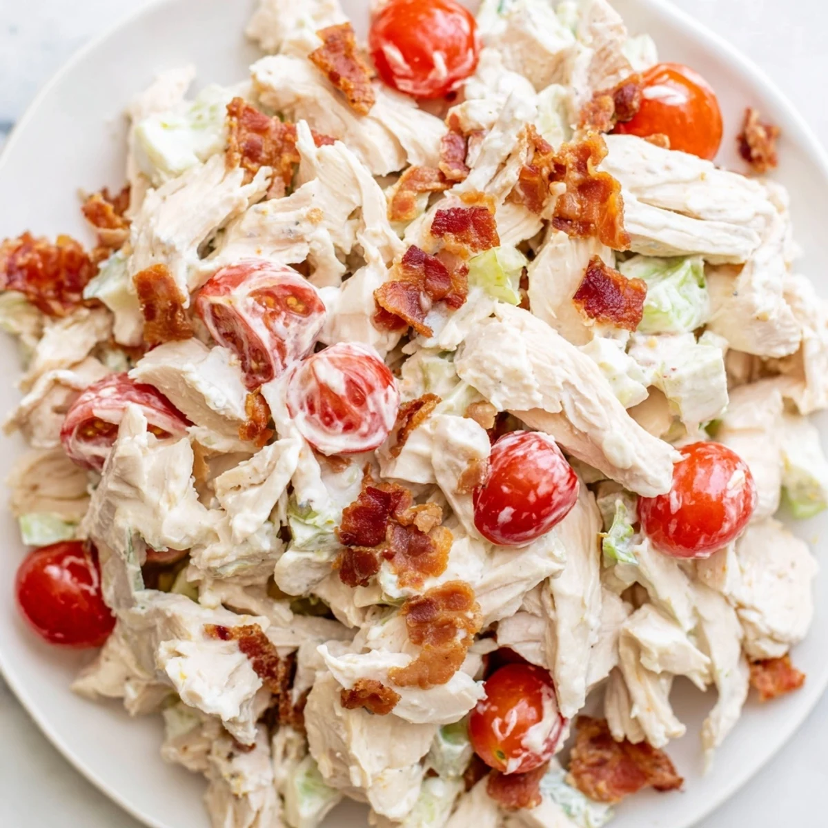 Sliced BLT Chicken Salad served on a chilled plate with avocado chunks and fresh herbs for a light lunch.