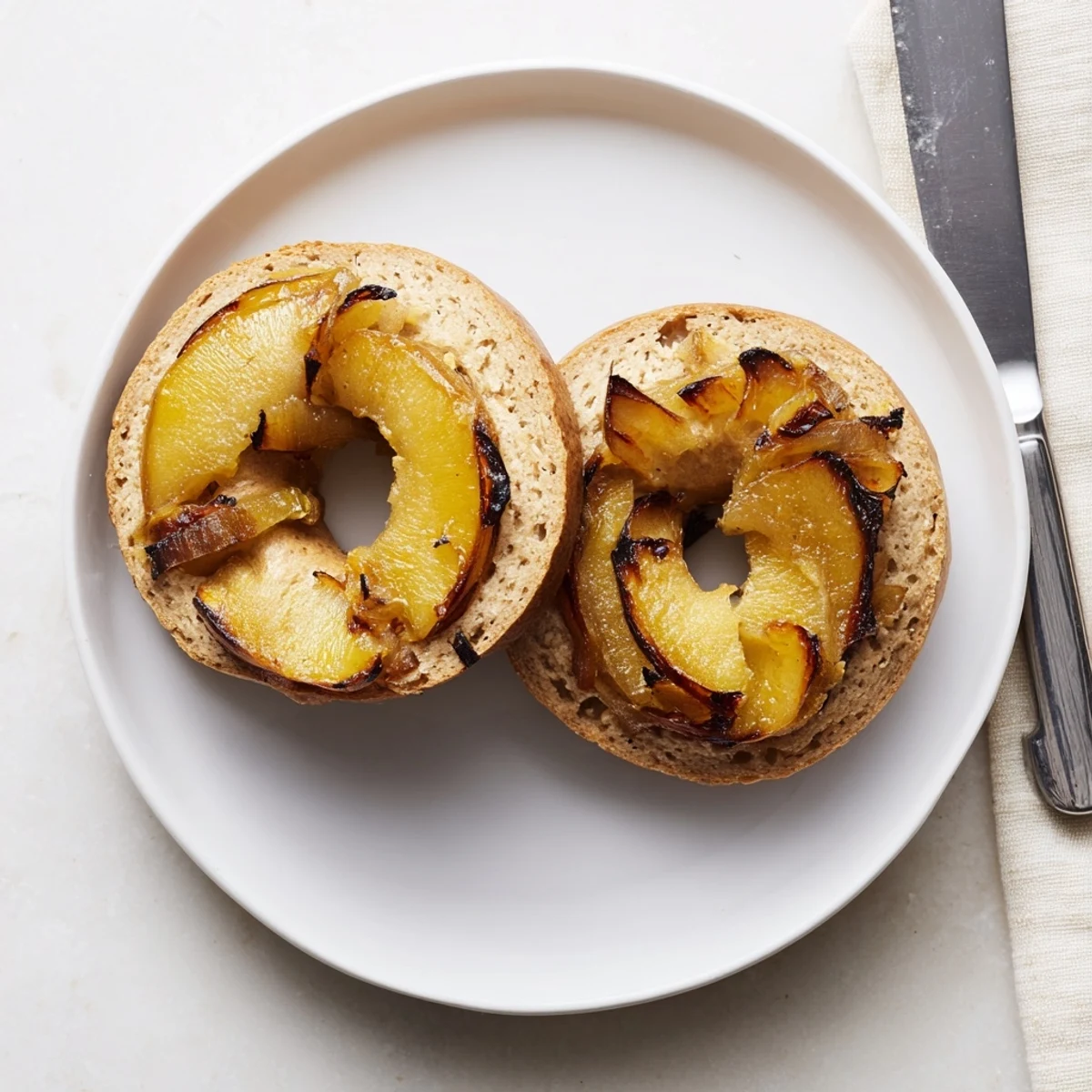 A close-up of warm Sourdough Onion Bagels highlights the glossy, savory onion topping and the distinctive chewy crumb, ready for breakfast.