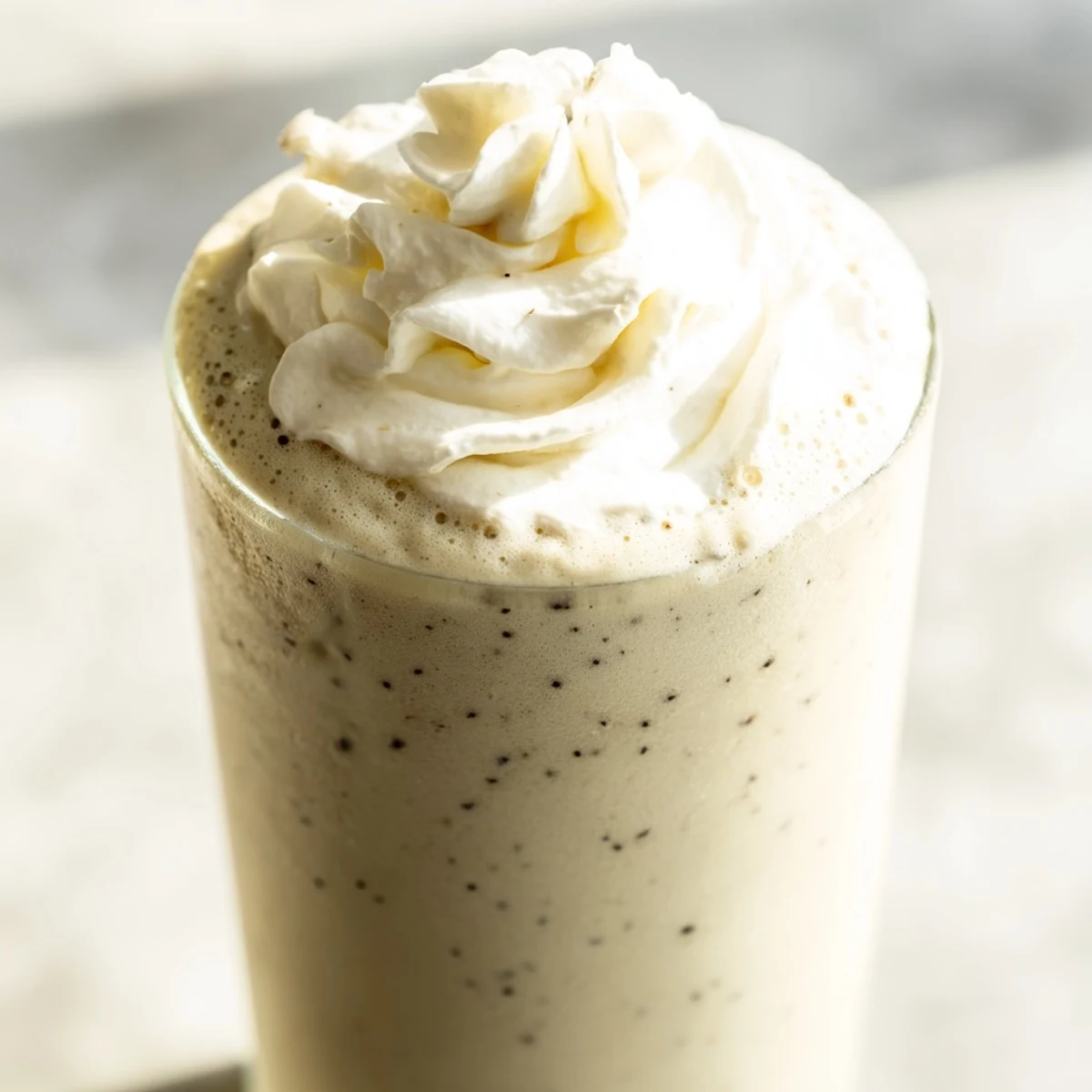 The Starbucks Vanilla Bean Frappuccino recipe features a creamy, blended beverage topped with whipped cream in tall glasses.  
