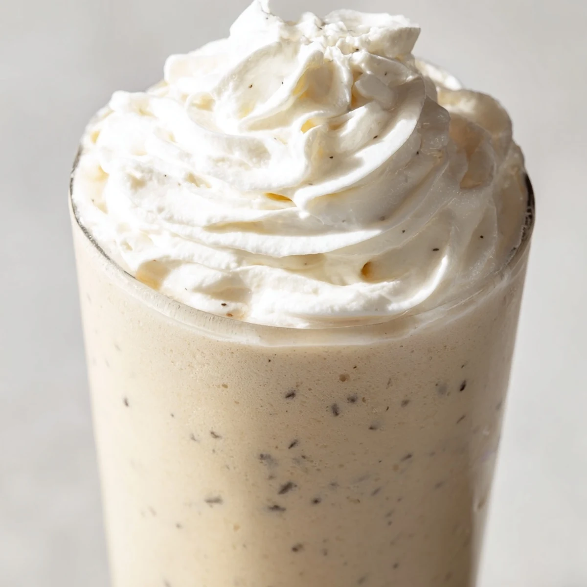 Serving suggestion for the Starbucks Vanilla Bean Frappuccino recipe, garnished with whipped cream and a straw on a marble counter.