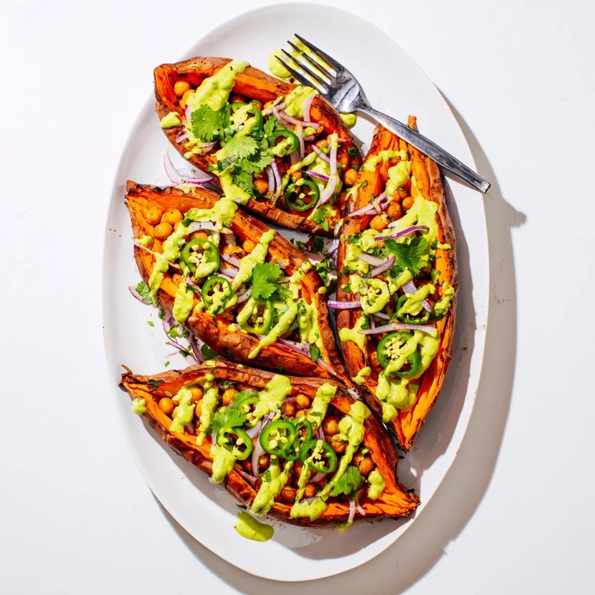 Piping hot Vegan BBQ Chickpea Sweet Potatoes served with jalapeño slices and a drizzle of sauce.
