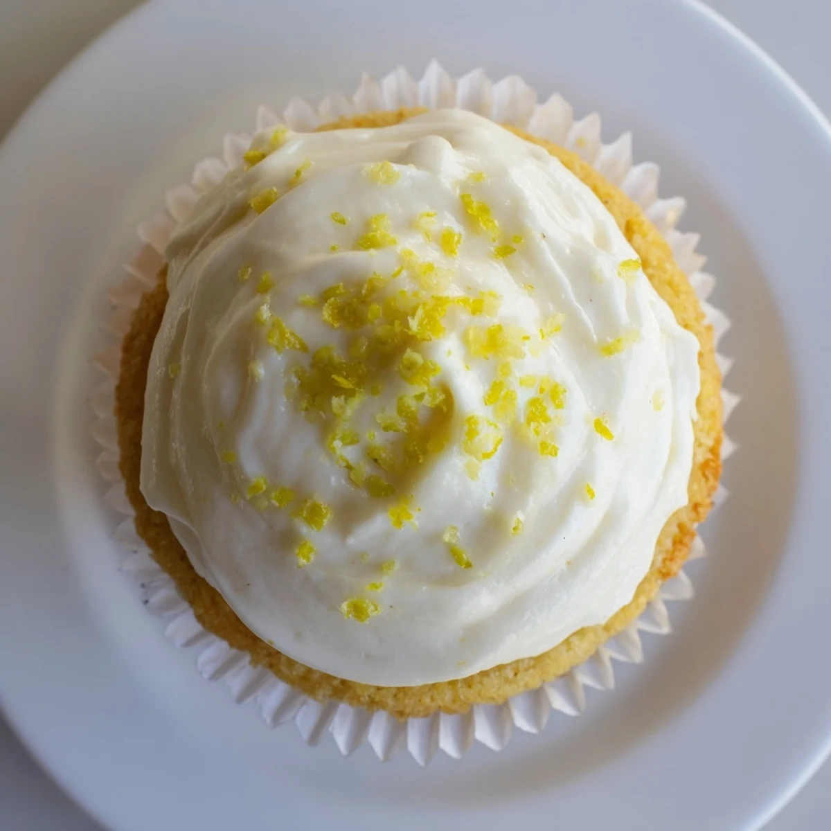 A close-up of a Limoncello cupcake shows moist crumb, Limoncello frosting, and lemon slice topping for summer entertaining.  