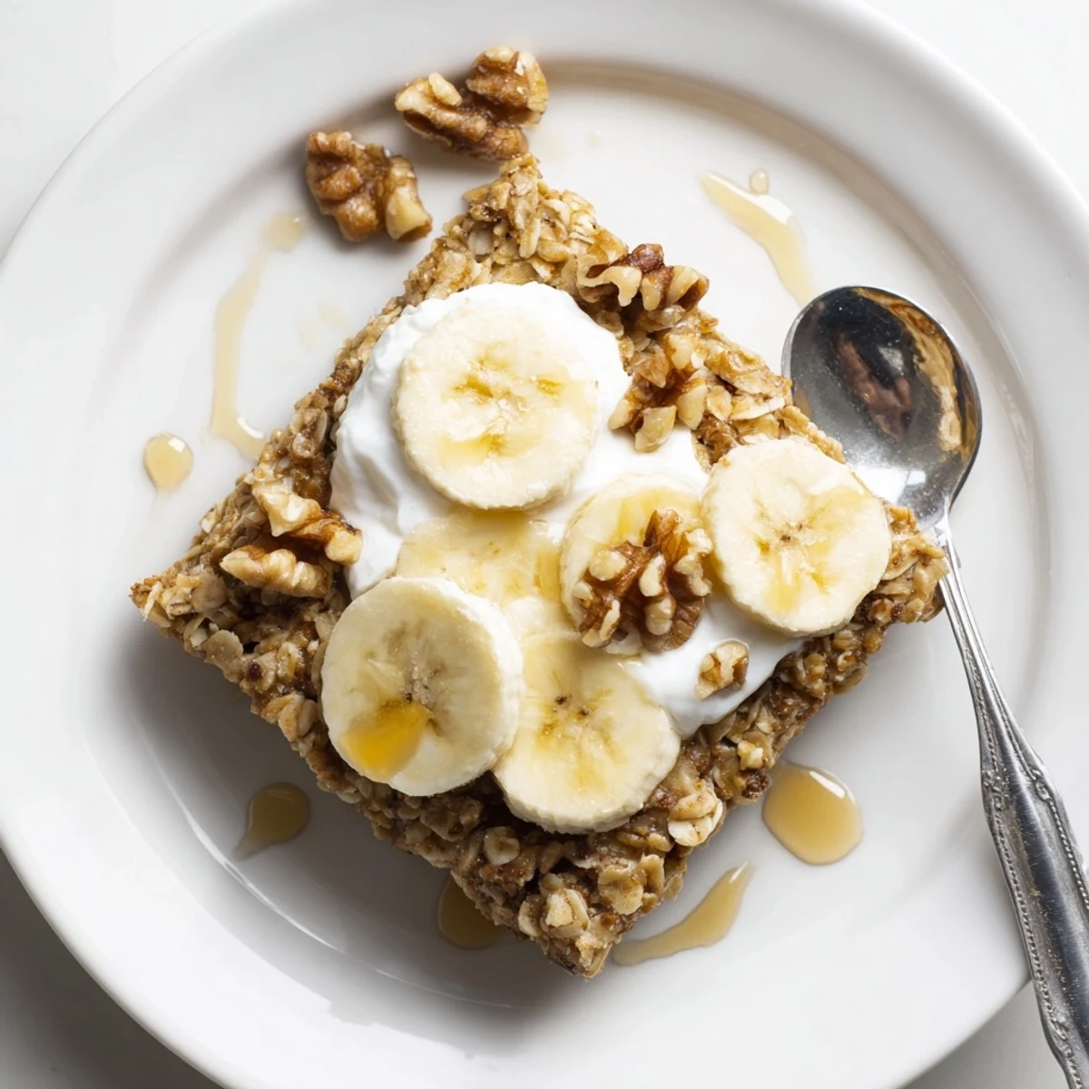 Warm Banana Baked Oatmeal with Greek Yogurt topped with a drizzle of maple syrup and fresh berries.