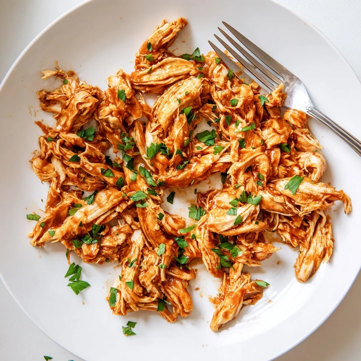 A close-up of Sweet Baby Rays Crockpot Chicken served over fluffy white rice, garnished with fresh parsley and a biscuit.