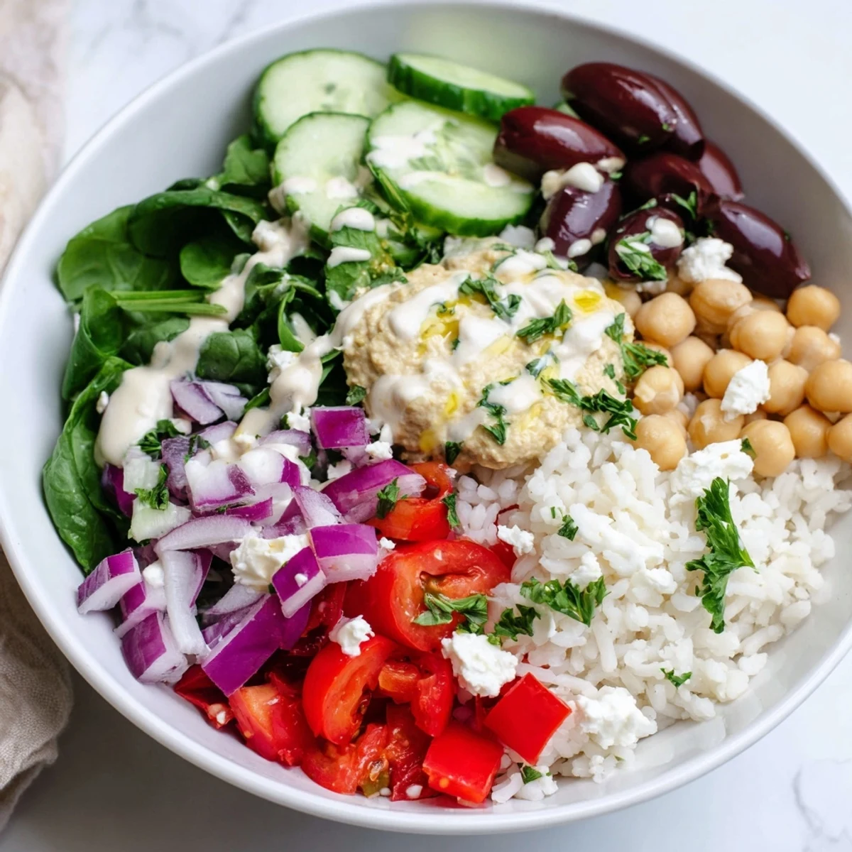Fluffy rice topped with fresh cherry tomatoes, cucumbers, chickpeas, and zesty lemon-tahini dressing in a Mediterranean rice bowl