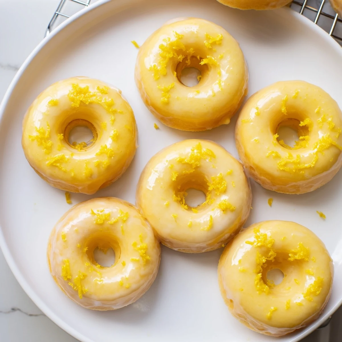Chewy gluten-free lemon mochi donuts topped with zesty icing and fresh lemon zest