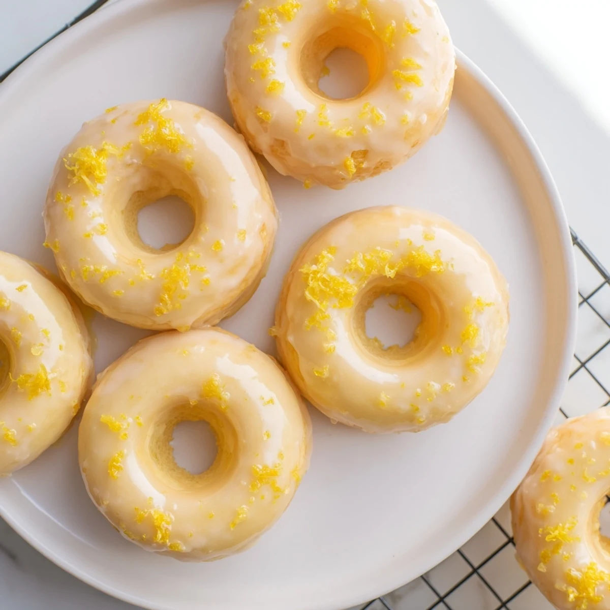 Golden lemon mochi donuts drizzled with white glaze on a wire cooling rack