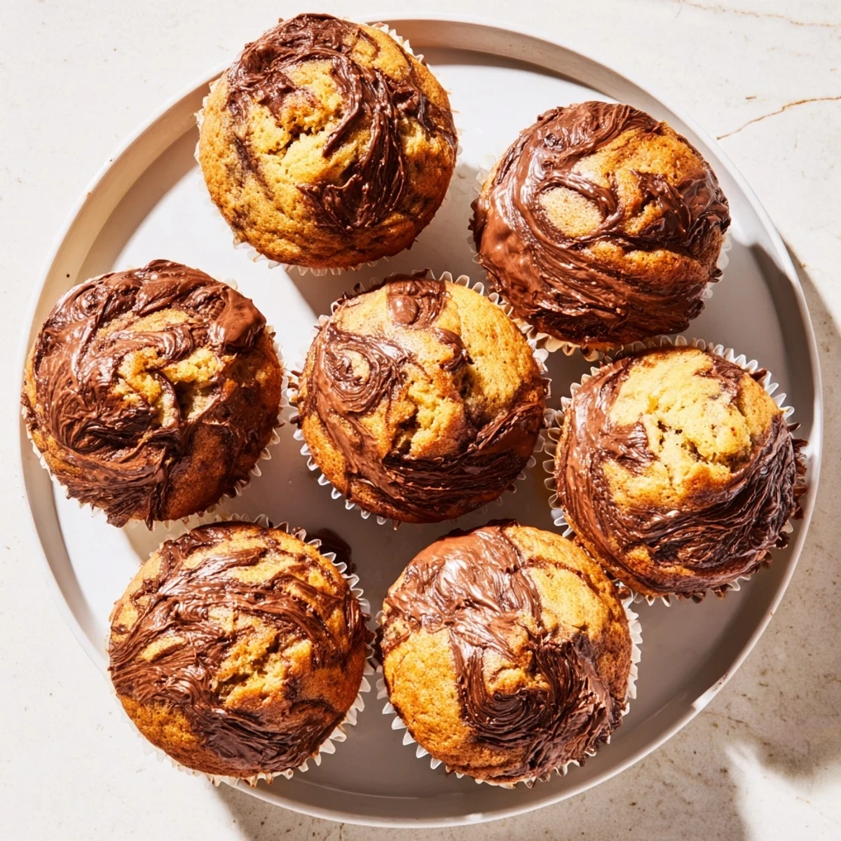 Freshly baked Nutella banana muffins with gooey chocolate centers cooling on a wire rack