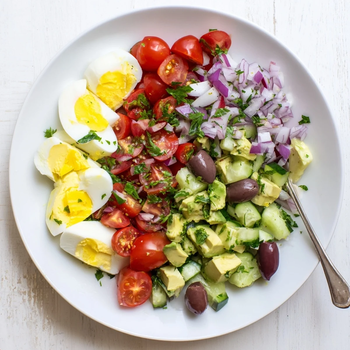 Creamy Mediterranean avocado egg salad served in a white bowl with colorful fresh vegetables