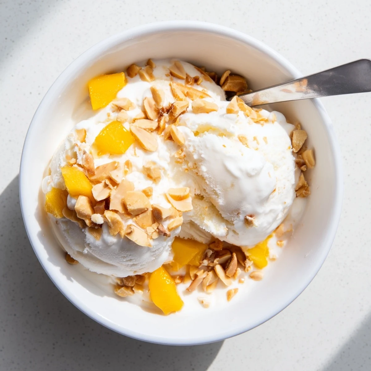Rich dairy-free Thai coconut milk ice cream served in a vintage glass dish with mango chunks