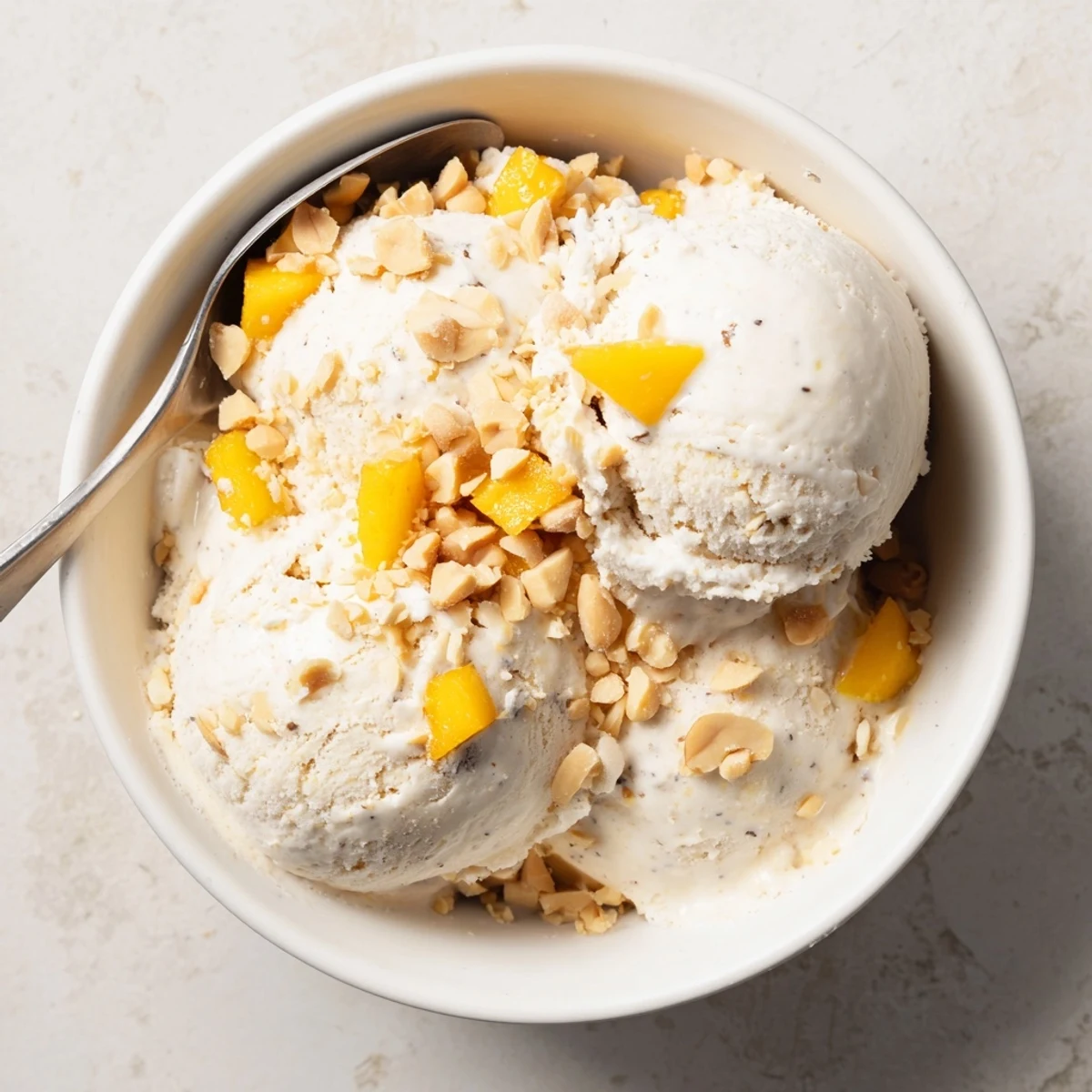 Smooth vanilla-infused Thai coconut milk ice cream piled high with roasted peanuts on a wooden board