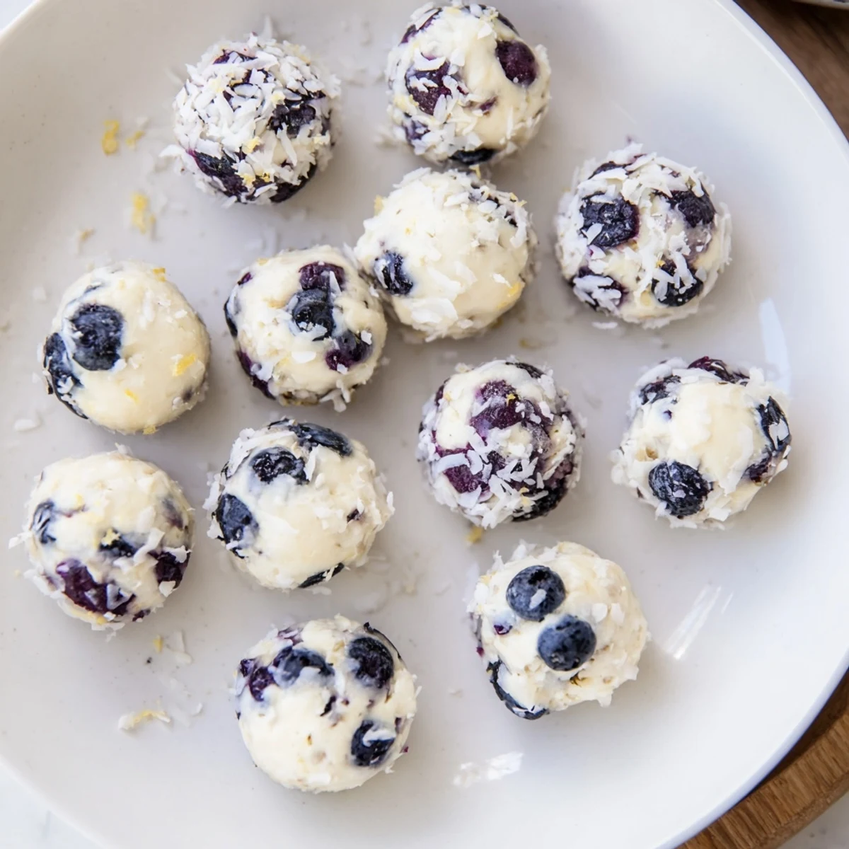 Creamy blueberry cheesecake protein bites rolled in coconut, ready for healthy snacking