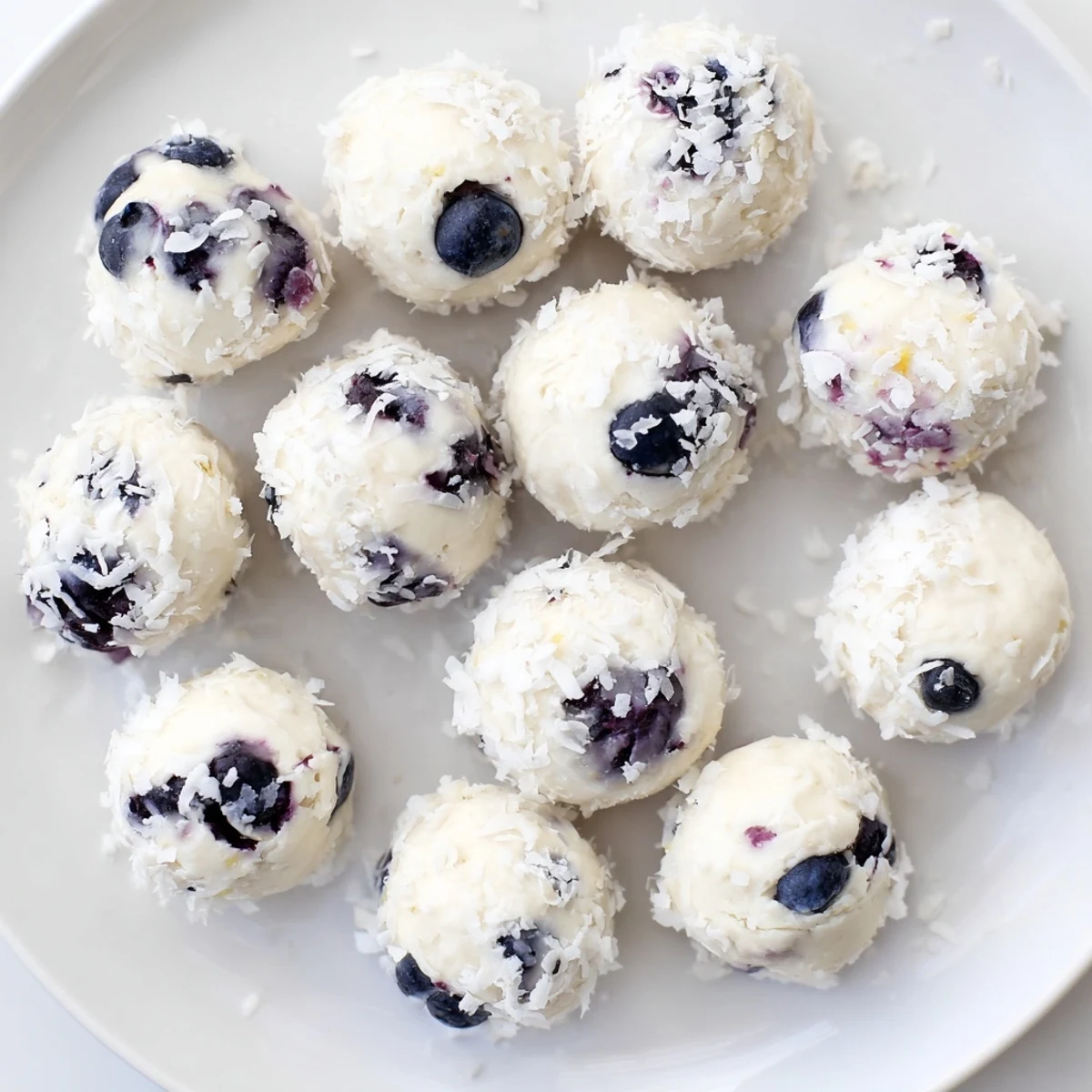 Close-up of bite-sized blueberry cheesecake protein treats bursting with purple berry swirls