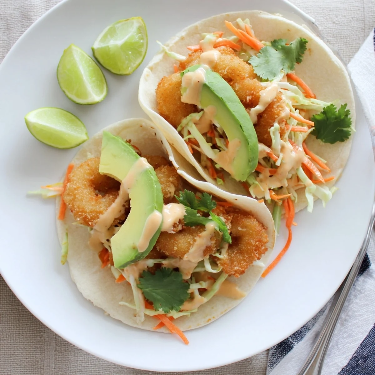 Golden crispy Bang Bang shrimp tacos loaded with colorful slaw and creamy spicy sauce