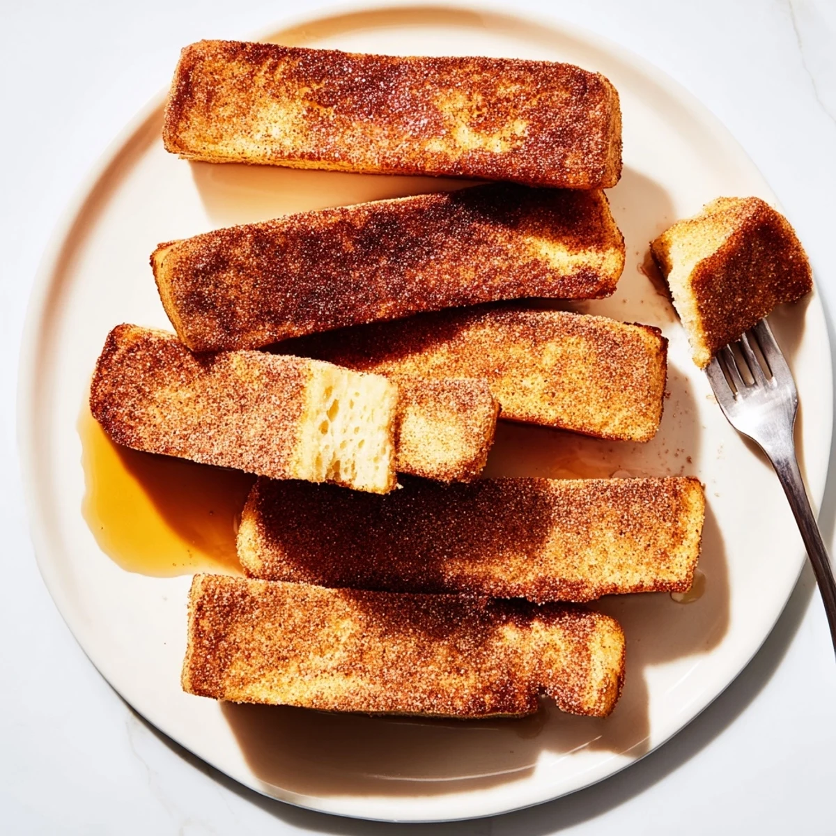 Crispy exterior cinnamon French toast sticks arranged on a plate, perfect finger food breakfast with sweet cinnamon sugar coating