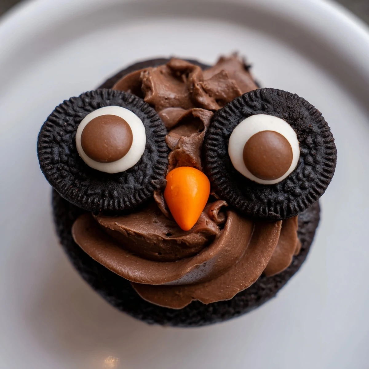Oreo Owl Cupcakes with fluffy chocolate frosting and candy eyes on a rustic baking sheet