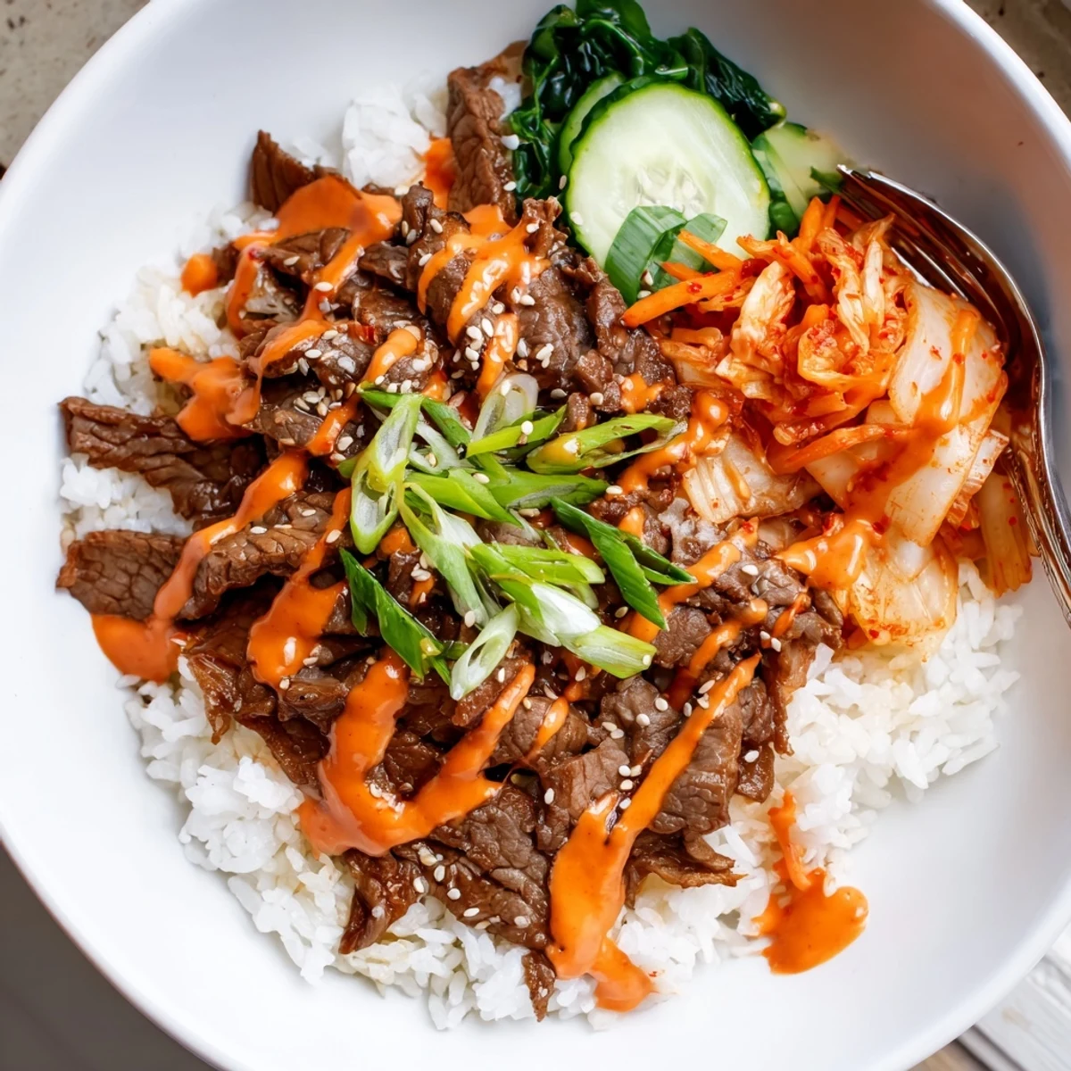 Caramelized steak over fluffy jasmine rice drizzled with spicy cream sauce in Korean BBQ steak rice bowls