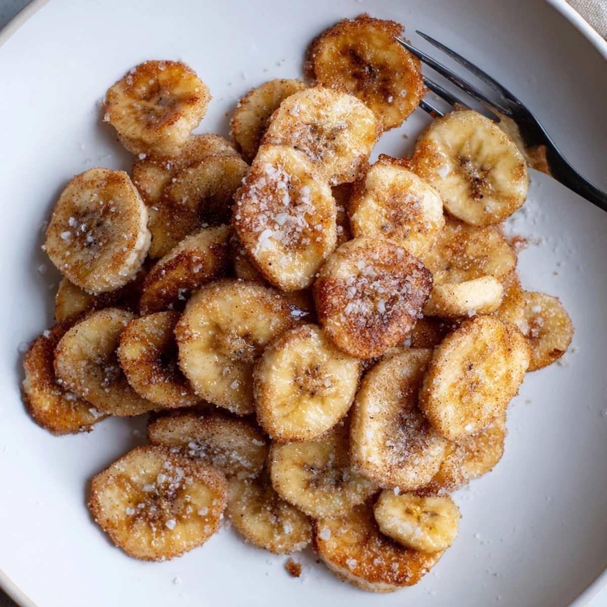 Warm Crispy Cinnamon Sugar Air Fryer Banana Chips piled on parchment paper.
