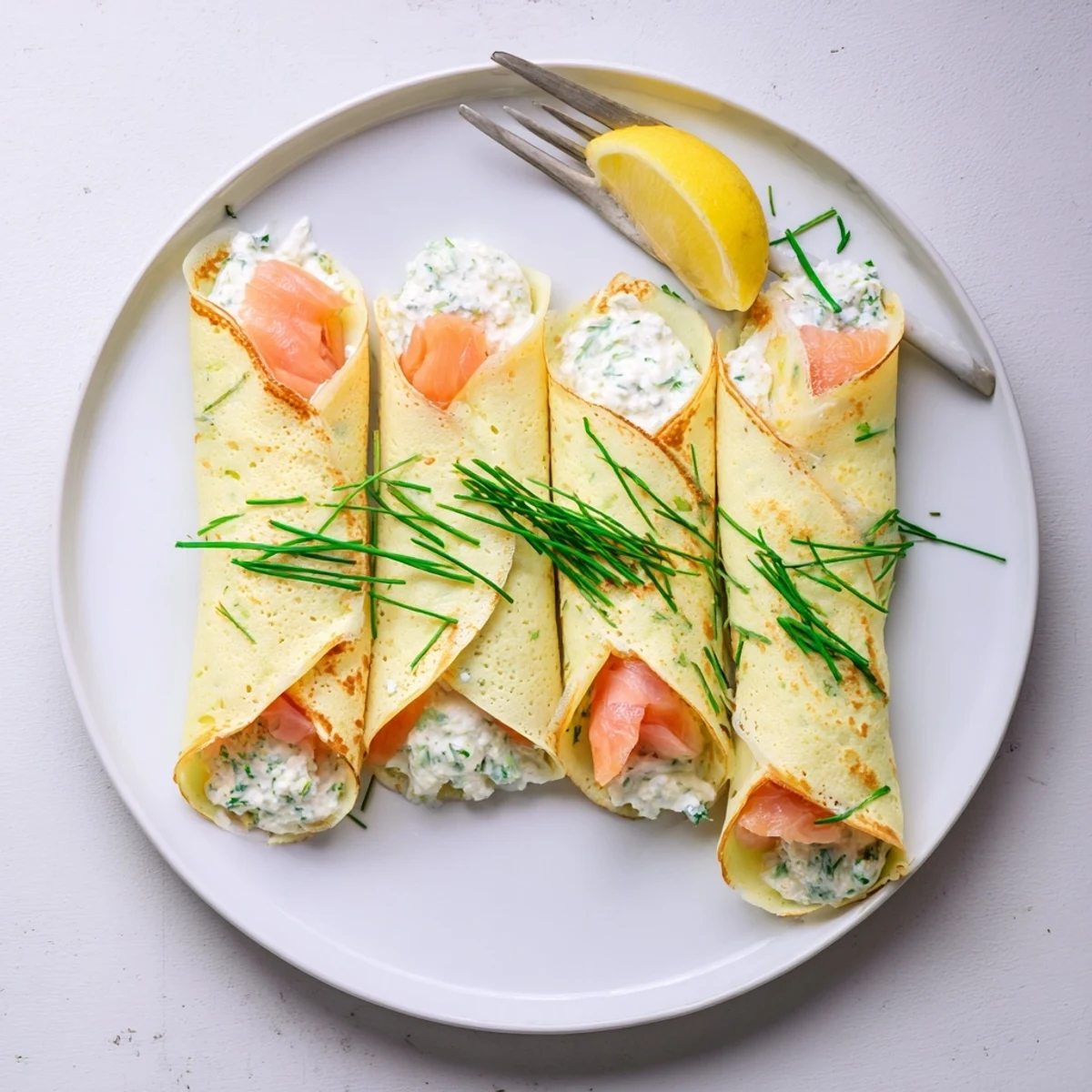 Elegant brunch plate featuring thin French crepes wrapped around silky smoked salmon with lemon wedges