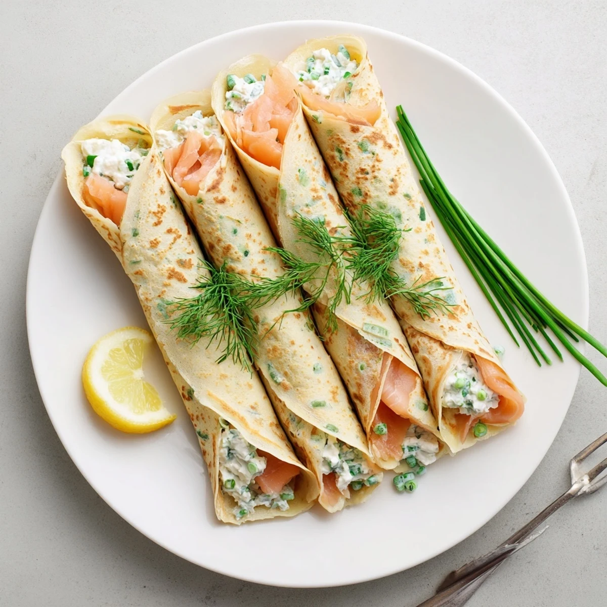 Golden rolled crepes filled with creamy herbed cheese and delicate smoked salmon slices garnished with fresh dill