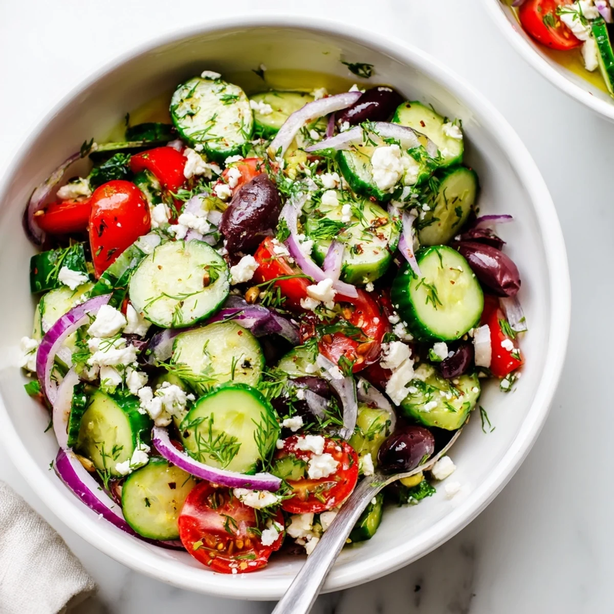 Colorful chopped cucumber salad featuring cherry tomatoes, Kalamata olives, and crumbled feta in olive oil dressing.