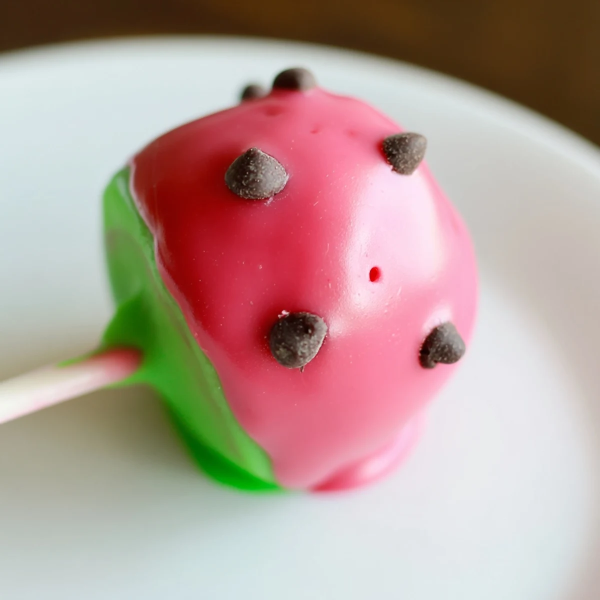 Summer dessert watermelon cake pops arranged on serving stand with creamy pink centers and green candy edges