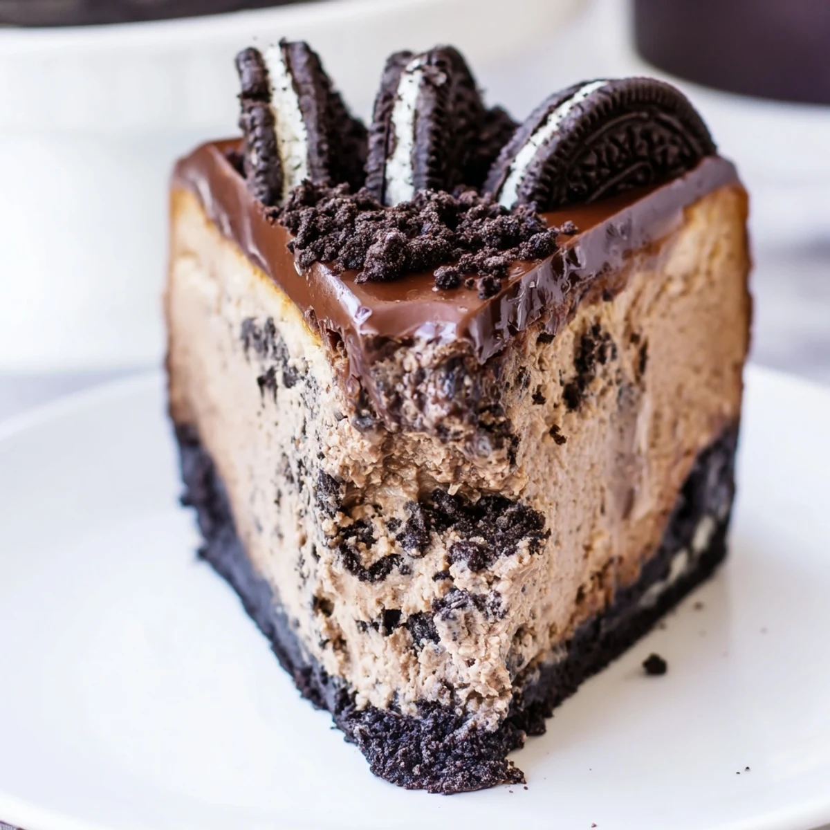 Decadent Oreo chocolate cheesecake drizzled with warm ganache on a dessert plate