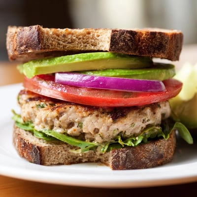 A plated Turkey Burger with Avocado featuring creamy avocado, red onion, and fresh toppings on a golden toasted bun.
